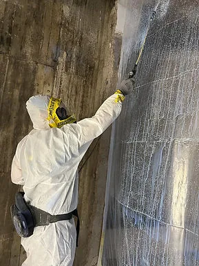 Medarbetare sanerar vägg i skyddsutrustning